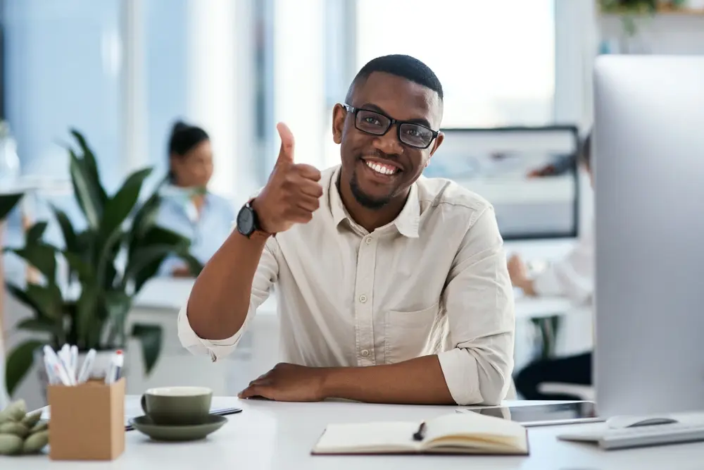 Smiling man giving a thumbs-up at his desk