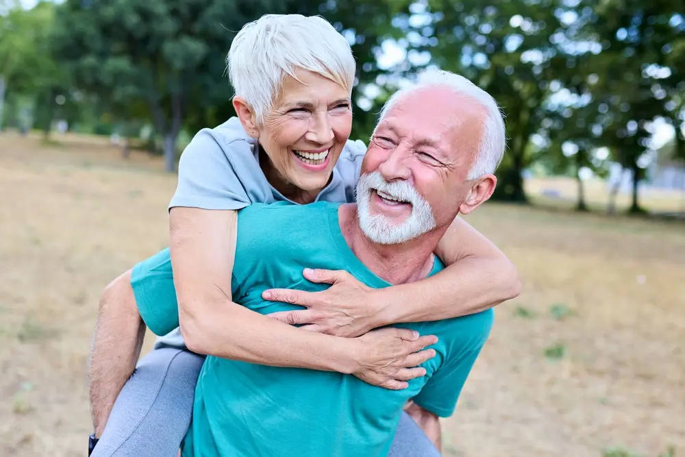 Laughing older couple, she rides piggyback on him