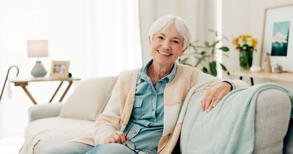 Smiling older woman seated on a sofa at home