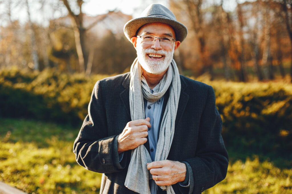 Smiling older man in a hat and scarf outdoors
