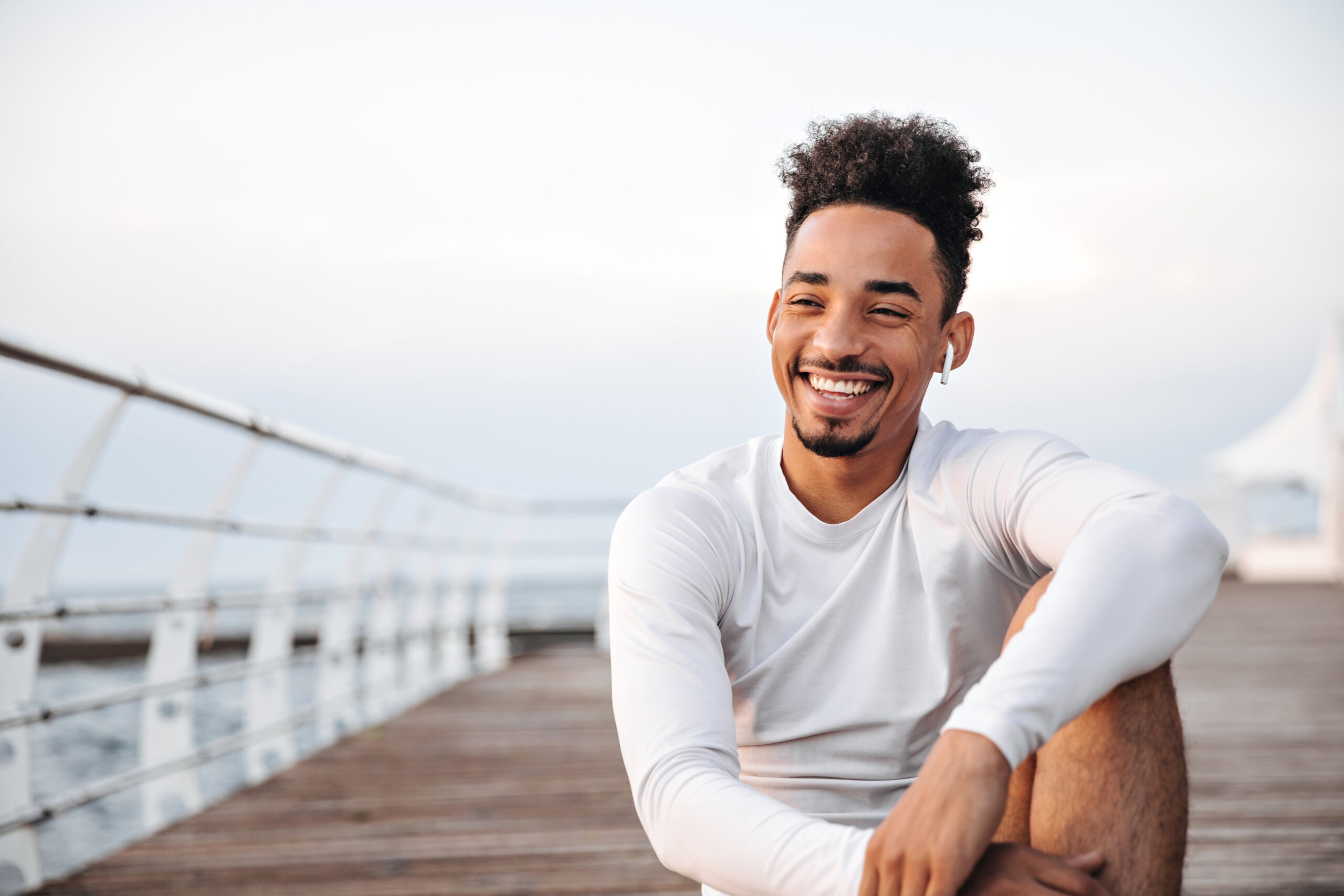 Smiling young man sitting on a boardwalk