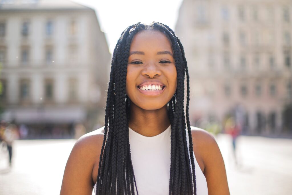 Smiling young woman with long braids on a city street