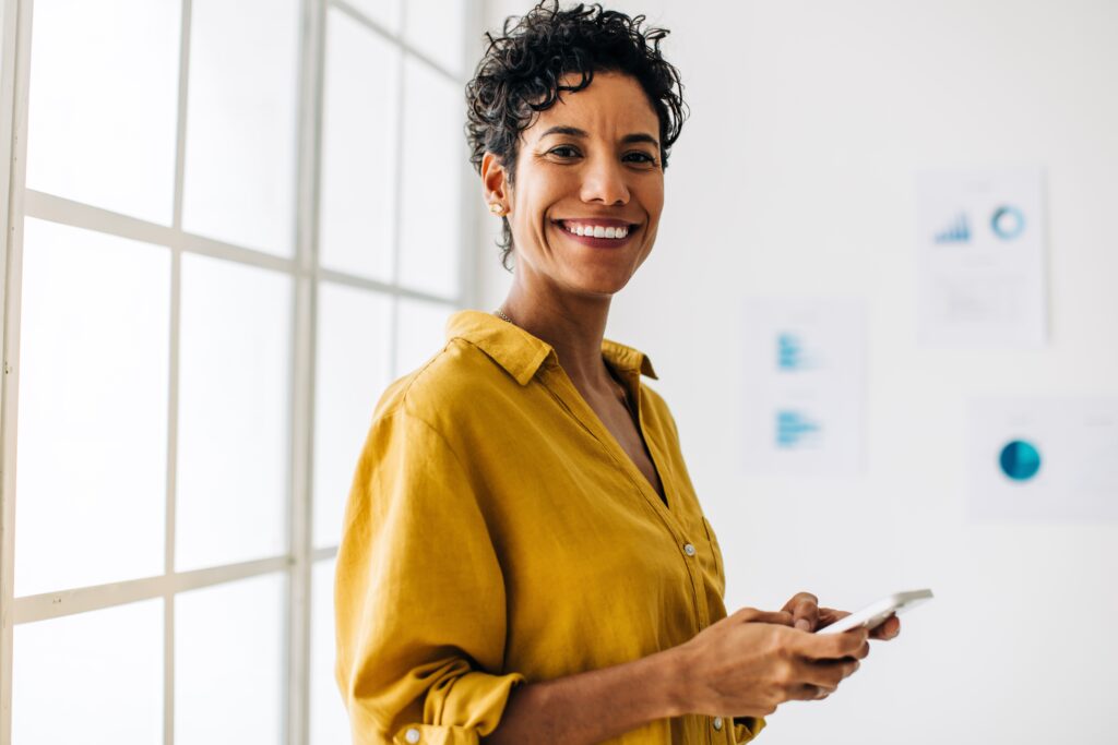 Smiling woman in a yellow shirt holding a phone