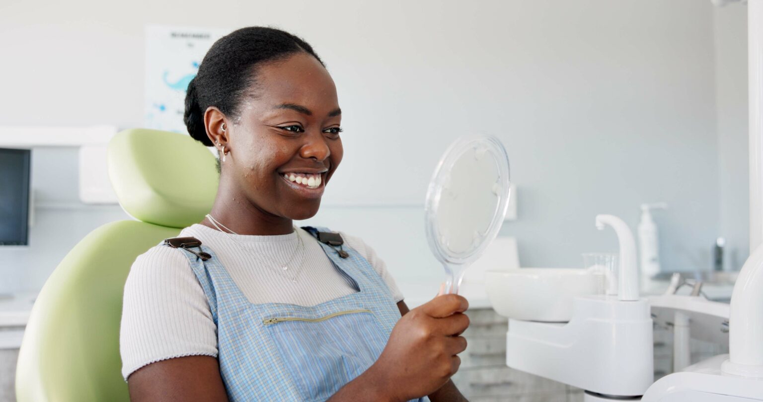 young woman looking in a mirror, new smile makeover